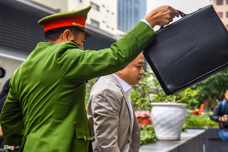 Vũ là 1 trong số 3 bị cáo bị tạm giam được dẫn giải đến tòa bằng xe thùng. Cựu Chủ tịch Công ty CP Xây dựng Bắc Nam 79 mặc vest, quần âu sáng màu. 