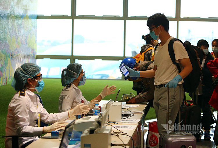 Khách nộp lại tờ khai cho nhân viên y tế ngồi tại sân bay 