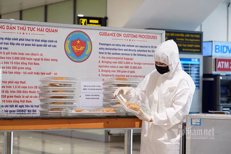 Nhân viên tổ bay đi qua khu vực đo thân nhiệt sau khi hoàn tất khai báo y tế. Nhân viên y tế Đoàn Hằng đang chuẩn bị các xuất ăn miễn phí