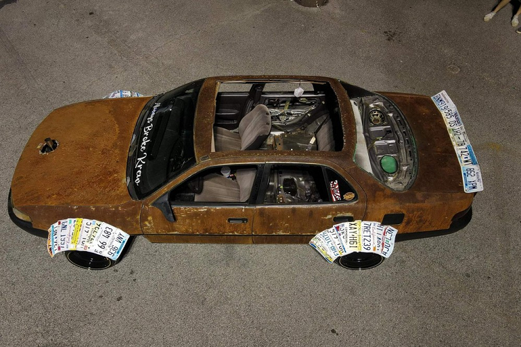 Chưa hết, chiếc Toyota Camry còn được bổ sung cánh gió sau theo phong cách "đuôi vịt". Tương tự chắn bùn, cánh gió đuôi này cũng được làm từ những chiếc biển số xe và hoàn toàn tương phản với màu gỉ sét. Lạ lùng hơn, chủ nhân của chiếc Toyota Camry đã tháo bỏ kính cửa sổ 2 bên, kính sau và khoét một lỗ lớn trên nóc xe. Ngay cả ống xả của chiếc sedan cỡ D cũng được thay đổi vị trí và chọc lên trên thông qua lỗ ở nắp ca-pô. Cuối cùng, chiếc Toyota Camry được lắp biển số không phải biển của nước Mỹ trên cản trước.