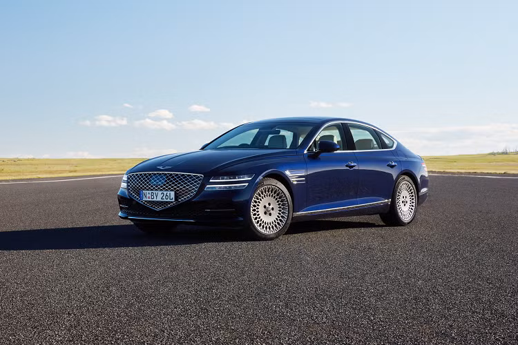  Genesis G80 2021 mới được áp dụng ngôn ngữ thiết kế thể thao thanh lịch, đơn giản những vẫn đầy xúc cảm. Xe được trang bị lưới tản nhiệt hình ngũ giác cỡ lớn với các mắt lưới dạng kim cương nổi bật. Nằm hai bên lưới tản nhiệt là cụm đèn pha thanh mảnh được chia thành 2 tầng. Những điểm nhấn nổi bật trên G80 2021 bao gồm mui xe dài, thân xe cơ bắp và bộ mâm hợp kim với thiết kế rất ấn tượng.