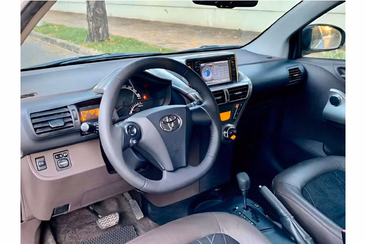 Ngoài ra các chi tiết như Logo Toyota, logo chữ, cánh lướt gió, ốp gương chiếu hậu và mui xe mang màu đen bóng đối lập với màu trắng thân xe tạo điểm nhất đầy mạnh mẽ cho tổng thể chiếc Toyota iQ.