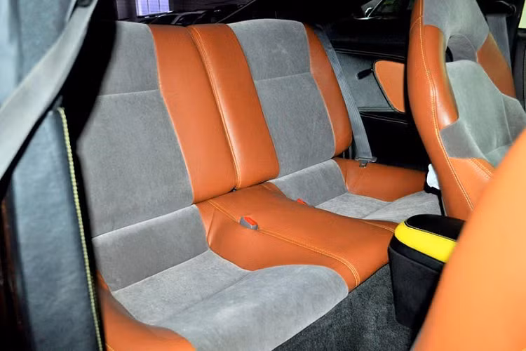 Đáng tiếc là những chi tiết này lại chẳng giống Lexus LC 500 chút nào. Bên trong chiếc Lexus LC 500 "nhái" này, chữ "Celica" vẫn còn nguyên trên ốp bậc cửa. Phần lớn nội thất đều được bọc da phối 2 màu đen - cam tương phản. Riêng trên ghế còn còn khu vực bọc nỉ màu xám lông chuột khá khó hiểu.