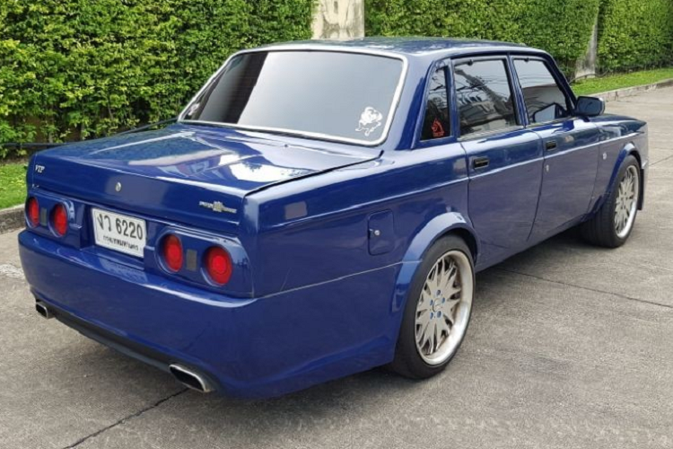 Vòng ra phía sau, chúng ta sẽ tìm thấy cụm đèn hậu được bê nguyên từ mẫu xe thể thao Nhật Bản Nissan Skyline thế hệ R32 sản xuất từ năm 1989 - 1994. Bên dưới là 2 ống xả hình chữ nhật và cản sau đầy đặn. Cuối cùng, chiếc Rolls-Royce Phantom "nhái" này được sơn màu xanh dương. Bên trong chiếc Volvo 240 "nhái" Rolls-Royce Phantom là nội thất "cổ lỗ sĩ" nhưng được bọc da màu đen phối chỉ đỏ tương phản. Ghế, mặt táp-lô và mặt cửa đều được phủ da khâu quả trám.