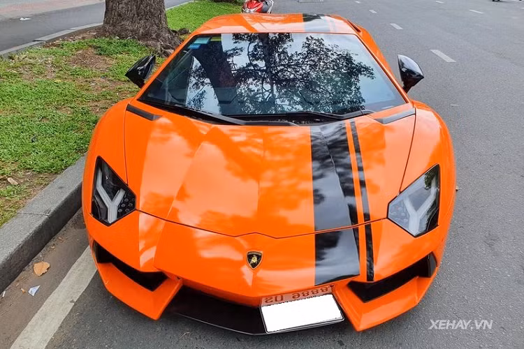 Về tay chủ mới ở Việt Nam không lâu, chiếc Lamborghini Aventador LP700-4 độ khủng này đã được "đổi màu" bằng cách dán decal màu cam bóng, kết hợp cùng sọc kẻ màu đen thể thao chạy dọc từ mũi xe ra đuôi xe.
