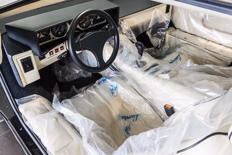 Màu sơn ngoại thất bóng như gương của chiếc siêu xe 30 tuổi. Nội thất bọc da màu trắng kem phối đen của chiếc Lamborghini Countach. Ghế và cửa vẫn được bọc ni-lông của hãng Lamborghini