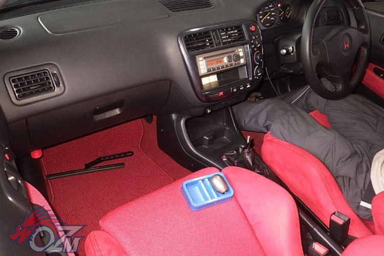 Cụ thể hơn, đây là một chiếc Honda Civic Type R đời 2000 và nó trông ngon lành đến độ ghế ngồi dường như chưa từng qua sử dụng. Hơn nữa, nó trông giống như một chiếc xe nguyên bản chưa từng độ, ngoại trừ lớp sơn màu đen che đi lớp sơn trắng ban đầu. Nội thất của xe trông vẫn còn mới, không hề có lấy một vết trầy, và nó cũng chỉ có chưa tới 2.600 km trên đồng hồ, tương đương chưa tới 130 km mỗi năm.