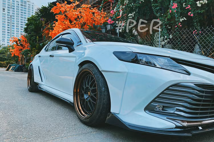 Được biết, bộ body thân rộng được thợ Việt thiết kế và đảm nhận luôn việc thi công. Ngoài 4 hốc bánh, chiếc Camry còn được định hình phong cách thể thao với bộ lip cản trước thể thao, nắp cốp cũng trang bị thêm đuôi gió trông “sexy” và mang chất chơi hơn. Chưa hết, xe còn lắp thêm bộ khuếch tán thể thao và ống xả. Xe còn được vô “dàn chân” lắp bộ mâm 3 mảnh Work VS XX, Nhật Bản.