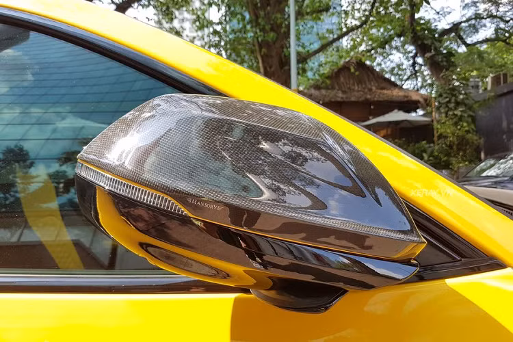Cận cảnh gương xe ốp carbon, logo Mansory với đường line vàng chạy ngang