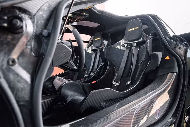 Khoang nội thất của Senna Merlin rất đơn giản với phong cách phối giữa các chi tiết carbon cùng những đường màu gold. Điều đặc biệt nhất trong khoang nội thất nằm ở phần bàn đạp với họa tiết trăng và sao được khắc laser đầy nổi bật, hợp nhất với phong cách “ma mị” của phiên bản cũng như truyền thuyết về Merlin. Trên bậc cửa ốp carbon, một họa tiết tạo hình pháp sư Merlin đã được trang bị làm cho phiên bản thêm phần độc đáo.