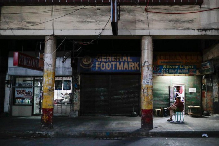Một người đàn ông ngồi bên ngoài các cửa hàng đóng cửa ngày 24/3 sau khi Manila, thủ đô Philippines, bị đặt dưới lệnh phong tỏa. 