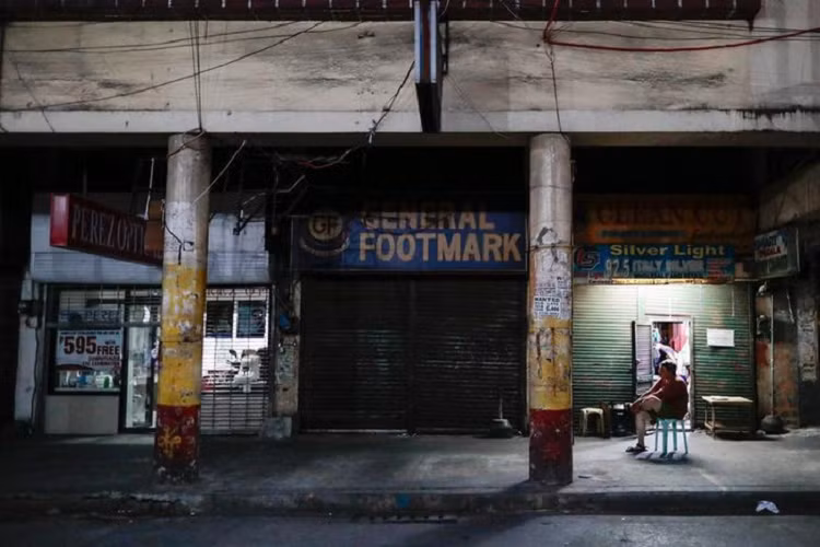 Một người đàn ông ngồi bên ngoài các cửa hàng đóng cửa ngày 24/3 sau khi Manila, thủ đô Philippines, bị đặt dưới lệnh phong tỏa. 