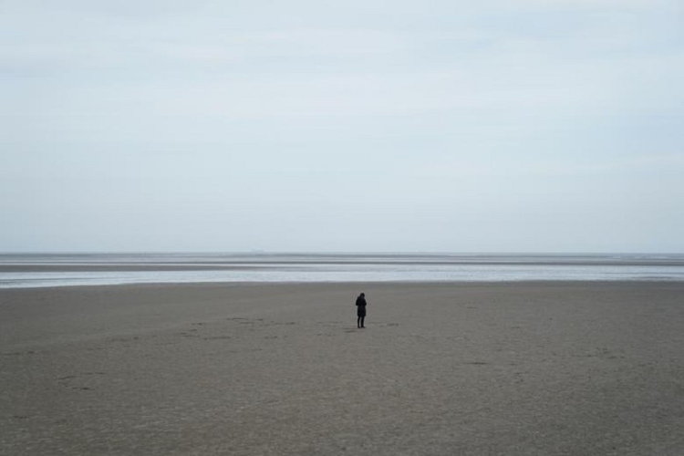 Một người phụ nữ đứng trên bờ biển Sandymount vắng người ở Dublin, Ireland, ngày 23/3.