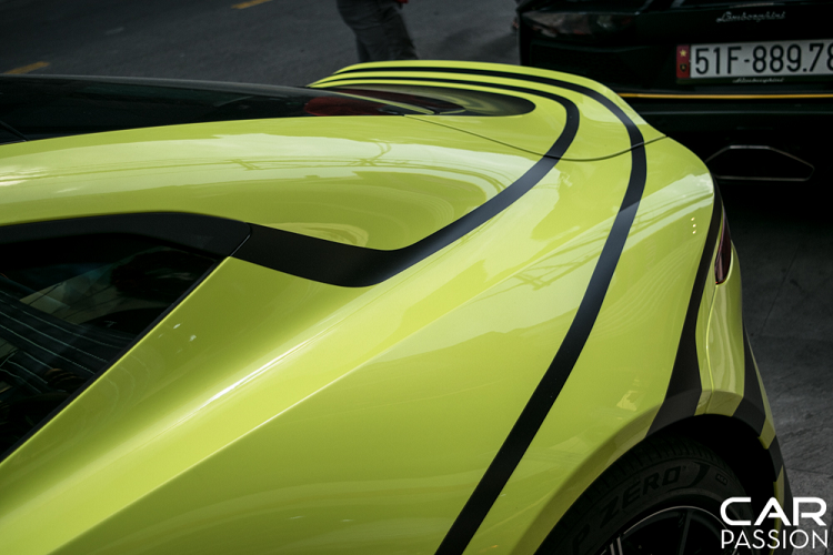 Hai bên thân xe được dán logo Aston Martin cỡ lớn với tông màu đen cùng các đường viền liền mạch chạy dọc thân xe tới phần đuôi. Phần nóc capo cũng được dán phối giữa hai tông màu đen-xanh. Với những họa tiết này, nền màu xanh đã không còn quá đơn điệu mà thay vào đó là một vẻ ngoài khác lạ, mới mẻ.