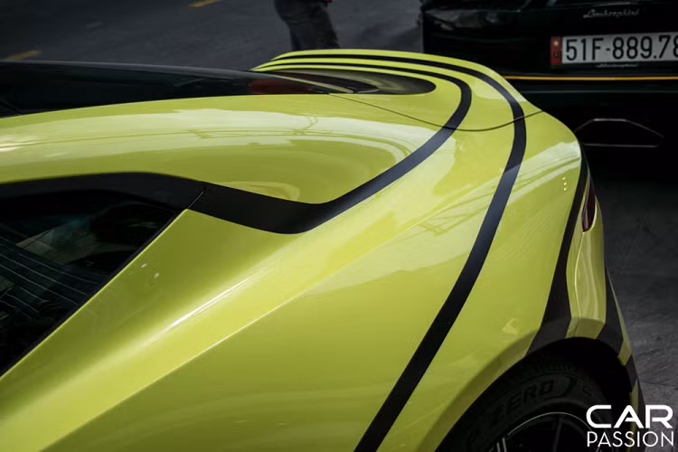 Hai bên thân xe được dán logo Aston Martin cỡ lớn với tông màu đen cùng các đường viền liền mạch chạy dọc thân xe tới phần đuôi. Phần nóc capo cũng được dán phối giữa hai tông màu đen-xanh. Với những họa tiết này, nền màu xanh đã không còn quá đơn điệu mà thay vào đó là một vẻ ngoài khác lạ, mới mẻ.