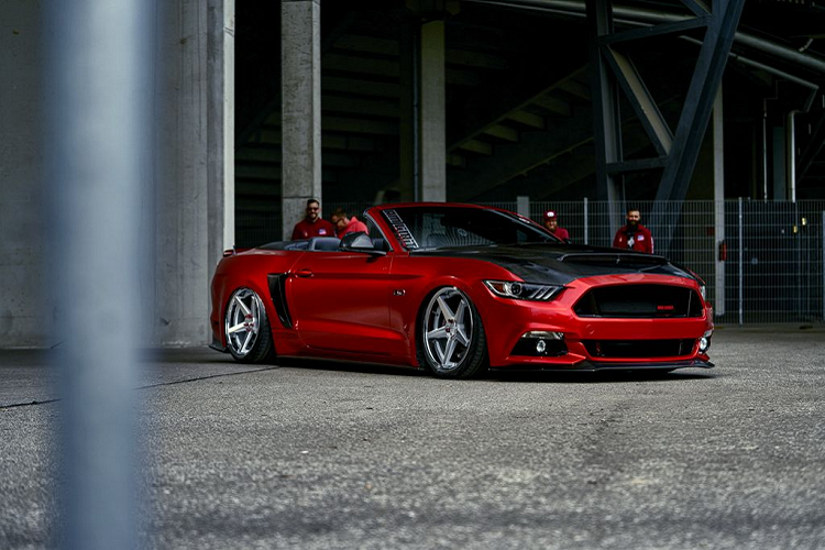 Đầu tiên, chiếc Ford Mustang GT Convertible độ này là một phiên bản tại châu Âu, cụ thể tại Đức. Và để tạo sự khác biệt, chiếc này đã khoác lên mình bộ body kit mới với các chi tiết hầm hố như bộ cản trước góc cạnh, các vây và tấm ốp bên hông, một bộ khuếch tán phía sau và cuối cùng là phần nắp capo với khe hút gió cỡ lớn, tất cả đều được làm từ sợi carbon.
