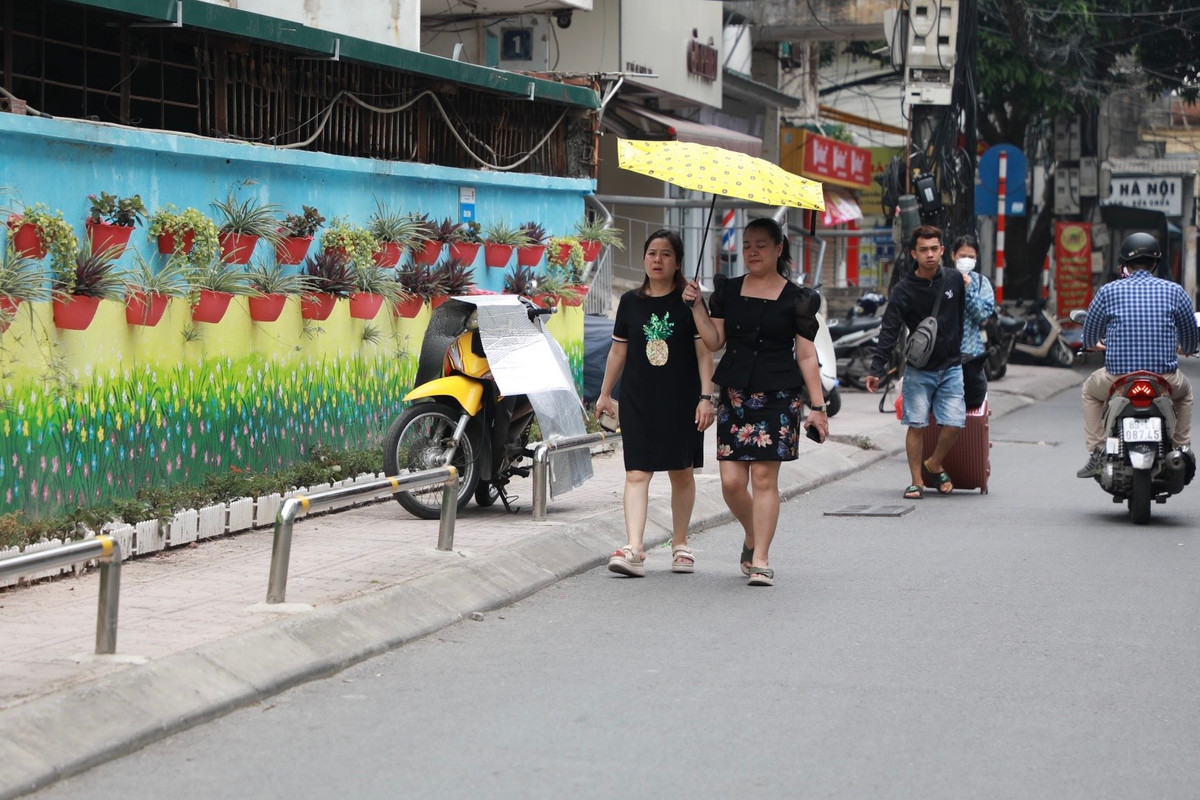 Một xe máy ngang nhiên đỗ trên vỉa hè, đẩy người đi bộ xuống lòng đường.