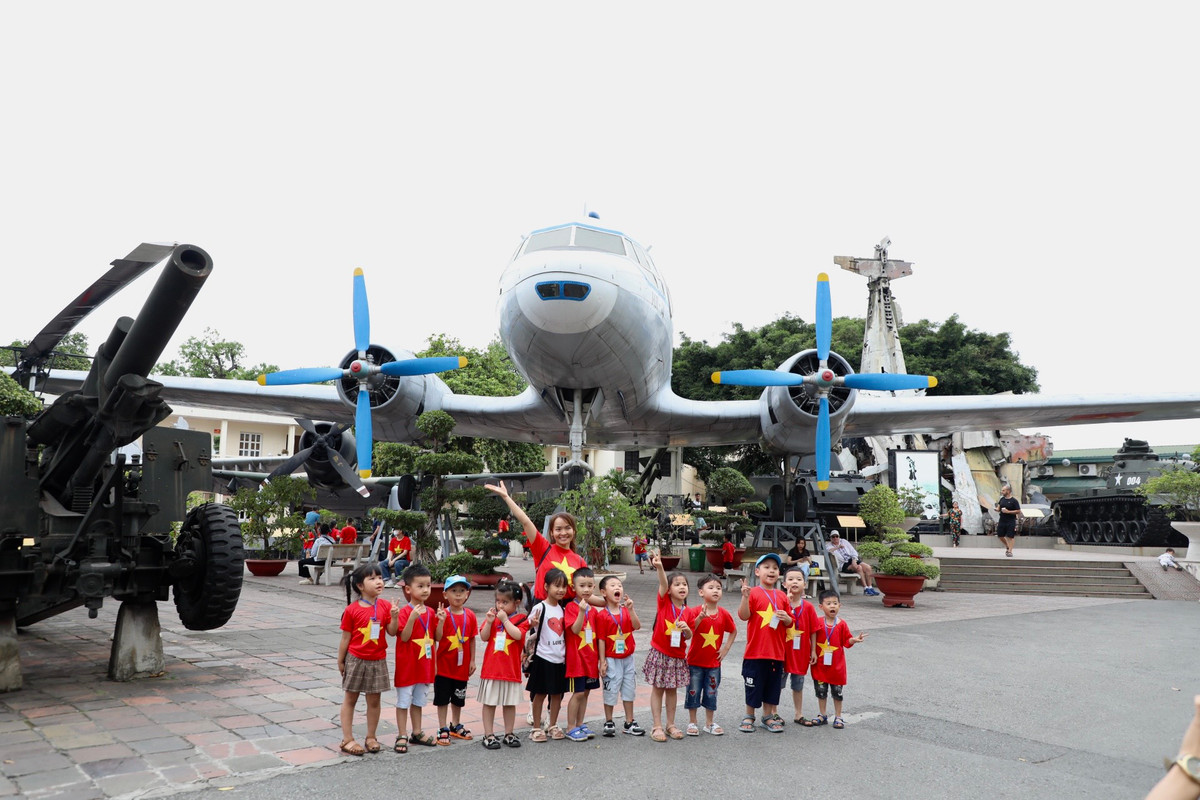 Các em nhỏ cùng cô giáo mặc áo cờ đỏ sao vàng chụp ảnh kỉ niệm bên chuyên cơ từng chở Bác Hồ.