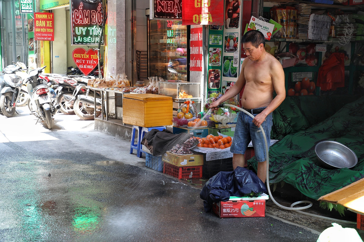 Để giảm nhiệt, nhiều người dân chủ động phun xịt nước làm mát mặt đường.