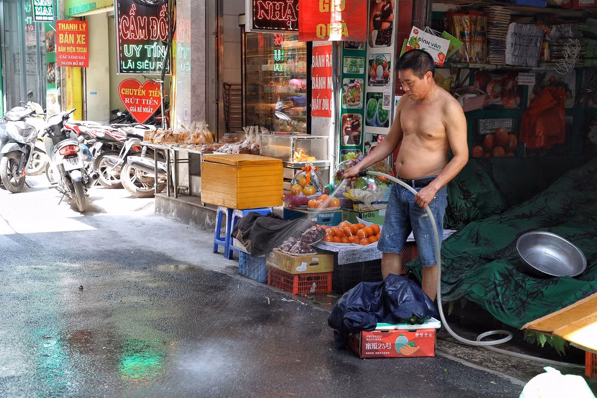 Để giảm nhiệt, nhiều người dân chủ động phun xịt nước làm mát mặt đường.