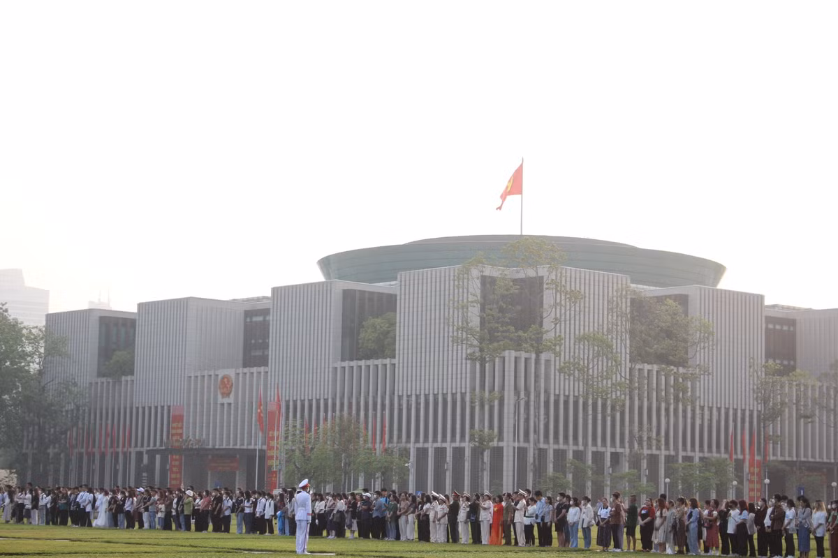 Trên Quảng trường Ba Đình, người dân dừng mọi hoạt động, nghiêm trang chuẩn bị dự lễ chào cờ.