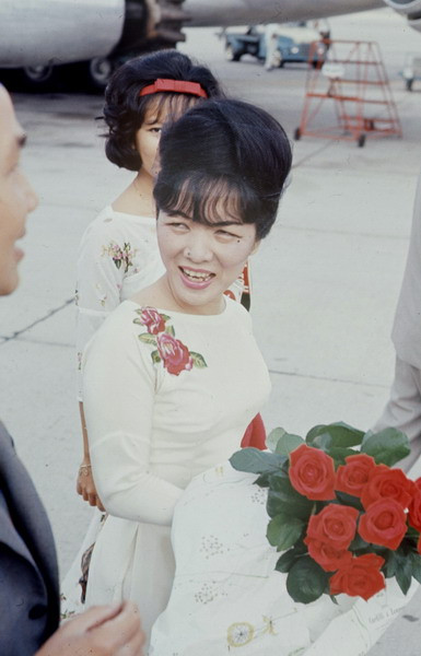 Khi ra sân bay, hai mẹ con mặc áo dài trắng thêu hoa. Ảnh: John Leongard.