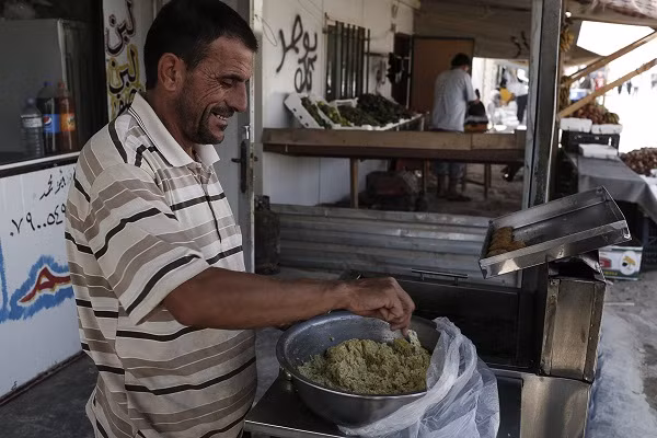 Abu Ashraf, 46 tuổi, đến từ Syria đang làm món falafel bên ngoài cửa hàng của anh ở trại tị nạn Zaatari.