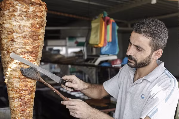 Từ Iraq tới Tanzania, Lebanon hay Cộng hòa Công-gô, hàng triệu người tị nạn trên khắp thế giới đang phải bươn chải cuộc sống nơi đất khách quê người. Họ cố gắng thích nghi cuộc sống mới nhưng luôn mong muốn một ngày nào đó được trở lại quê nhà. Ảnh: Mohamad al Hraki đang làm việc trong một nhà hàng của chú ở trại tị nạn Zaatari, Jordan.