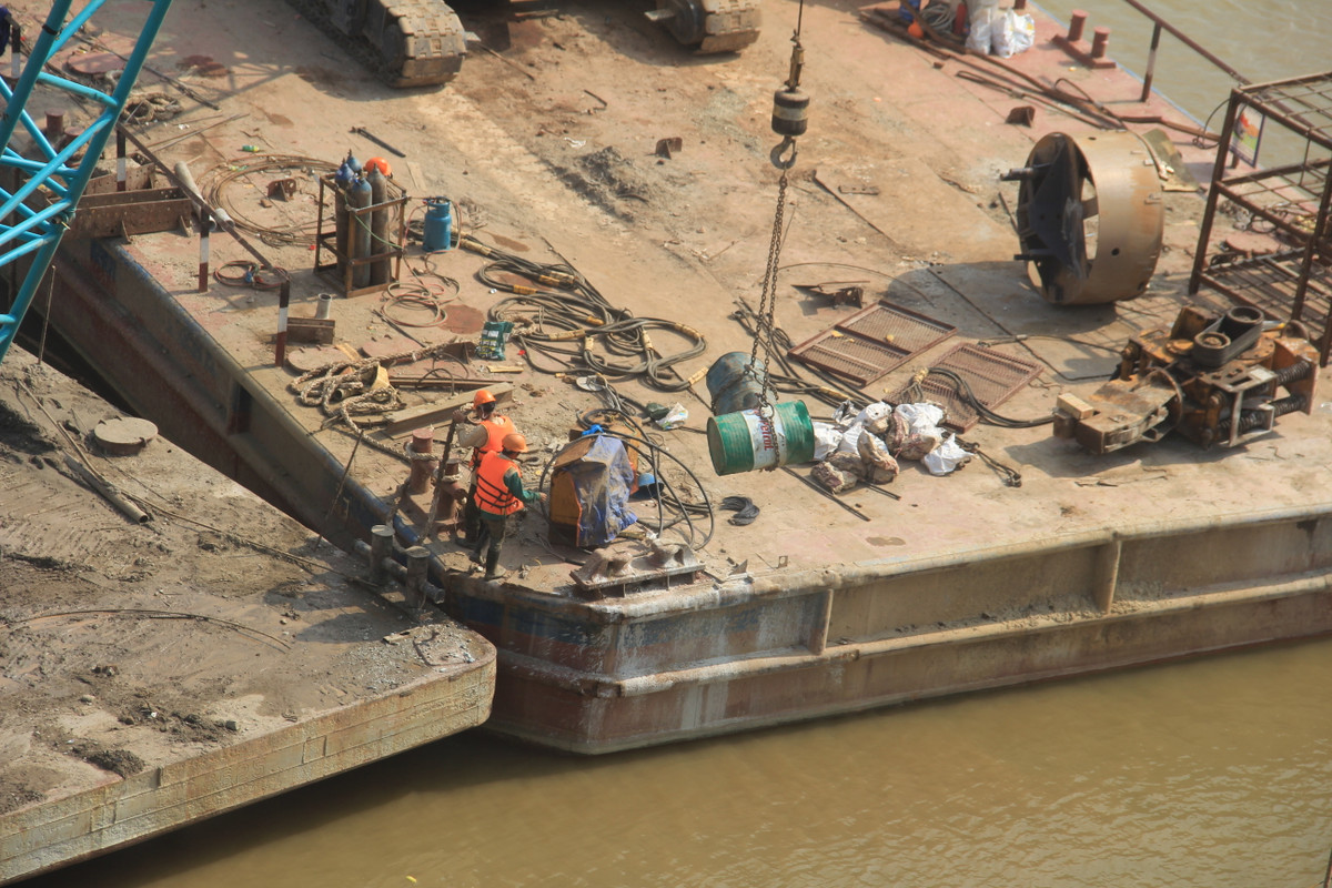 Nhiều xà lan được nối thành đường nổi cho xúc, cần cẩu ra khoan đào trụ ở lòng sông, sau đó đóng cọc cừ xung quanh phạm vi đổ trụ. 