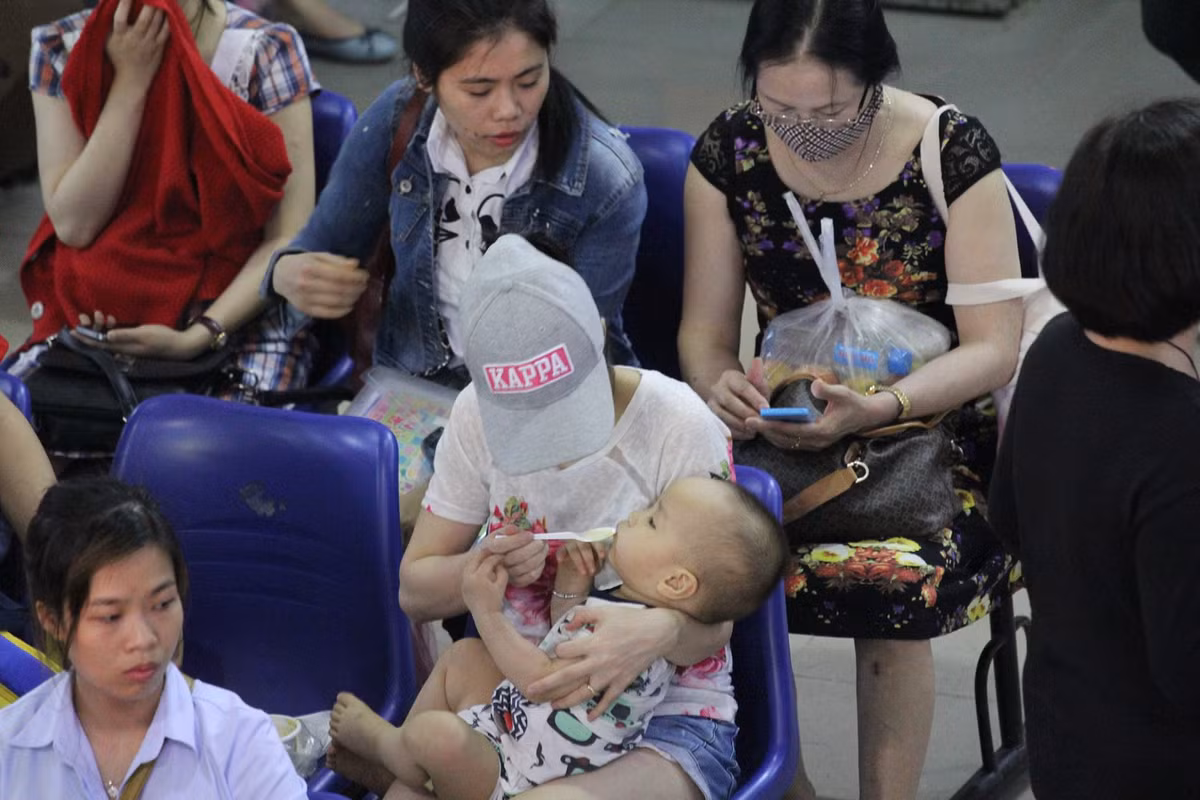 Nhiều người tranh thủ cho con ăn trong lúc chờ xe - Ảnh: Sóng nghệ.