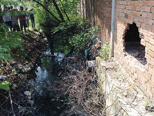 Bức tường của xưởng cơ khi bị thủng một lỗ lớn, một thi thể nam thanh niên nằm vắt vẻo trên lỗ thủng này. Hai người còn lại nằm dưới mương nước.