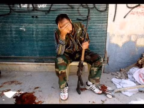 Một tay súng ở Syria ngồi bên những vết máu sau khi đồng đội của anh ta vừa bị bắn hạ. Nguồn ảnh: WN.