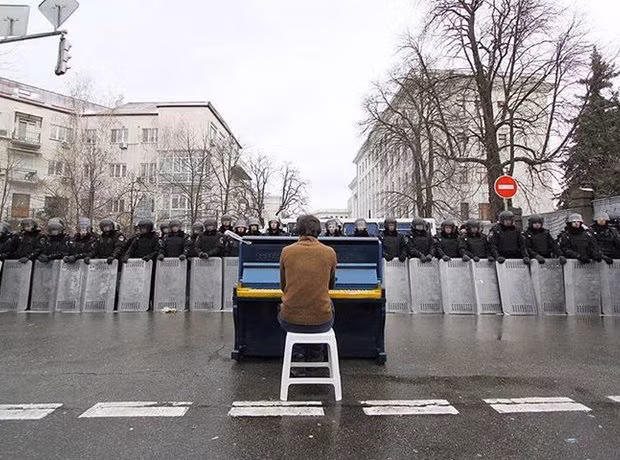 Một người đàn ông ngồi chơi piano trước hàng dài cảnh sát trong cuộc bạo loạn ở Ukraine năm 2014. Nguồn ảnh: Classic.