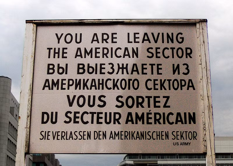 Sau khi phía Đông Đức và Liên Xô xây dựng bức tường Berlin, người dân Berlin không còn được phép tự do qua lại giữa hai phần thủ đô nữa mà buộc phải đi qua các trạm kiểm soát, Trạm Charlie là một trong số đó. Ảnh: Biển báo nổi tiếng có viết "Bạn đang rời khỏi khu vực của Mỹ" bằng 4 thứ tiếng khác nhau. Điều khiến bức biển báo này nổi tiếng đó là nó được đặt ở Trạm C, trong lòng thủ đô nước Đức nhưng lại được ghi là "khu vực của Mỹ". Nguồn ảnh: Commons.