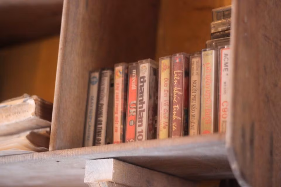 Những chiếc băng cassette cũ kỹ được xếp ngay ngắn ở một góc giá sách trong không gian quán, gợi nhớ về một thời đã qua.