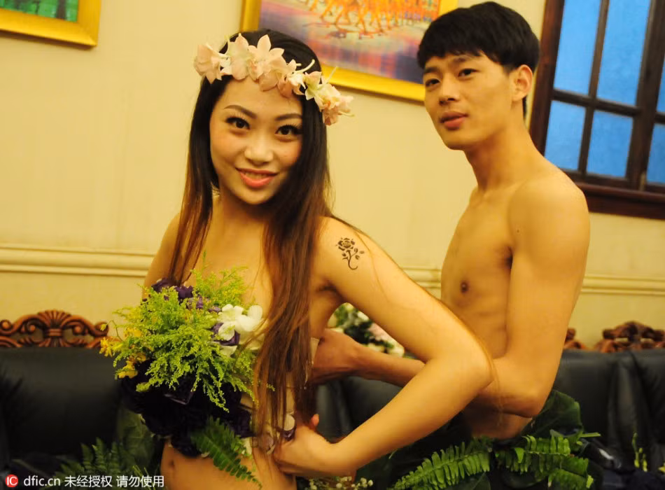 Trong phòng thay đồ, người chồng đang chỉnh trang phục cho vợ.