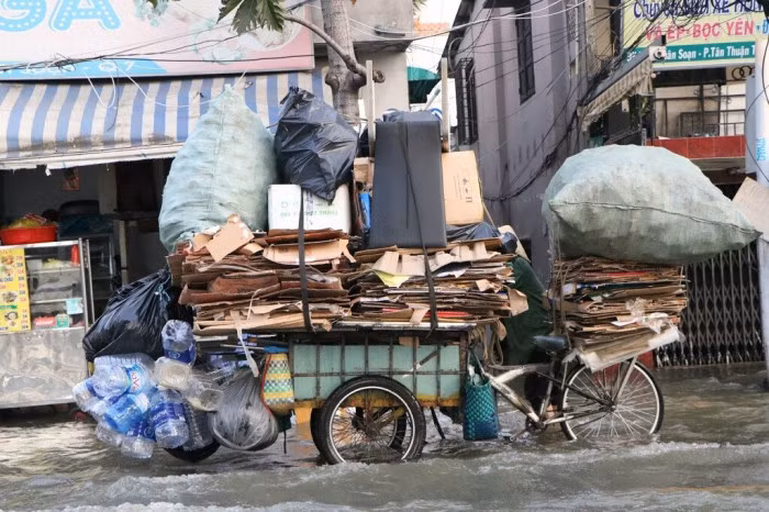 Người phụ nữ nhặt ve chai đẩy xe vượt biển nước.