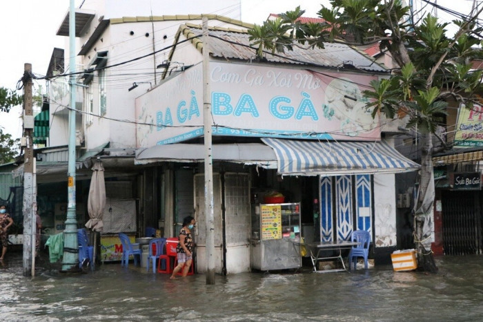 Nước ngập tràn vào quán sá, người dân phải tát nước ra bên ngoài, cuộc sống kinh doanh của người dân trên tuyến đường này bị đảo lộn.