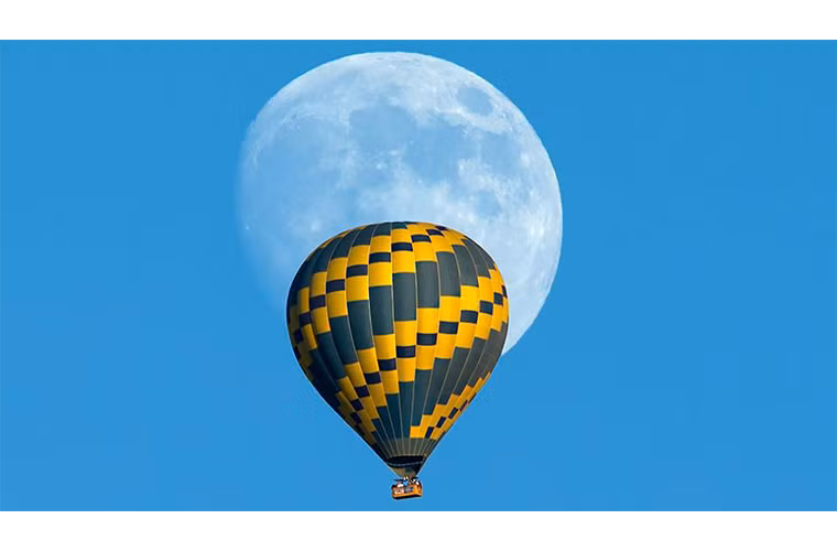 Một khinh khí cầu đang bay qua Mặt trăng tròn trong một buổi chiều mùa thu ấm áp gần thành phố biển Encinitas, California.