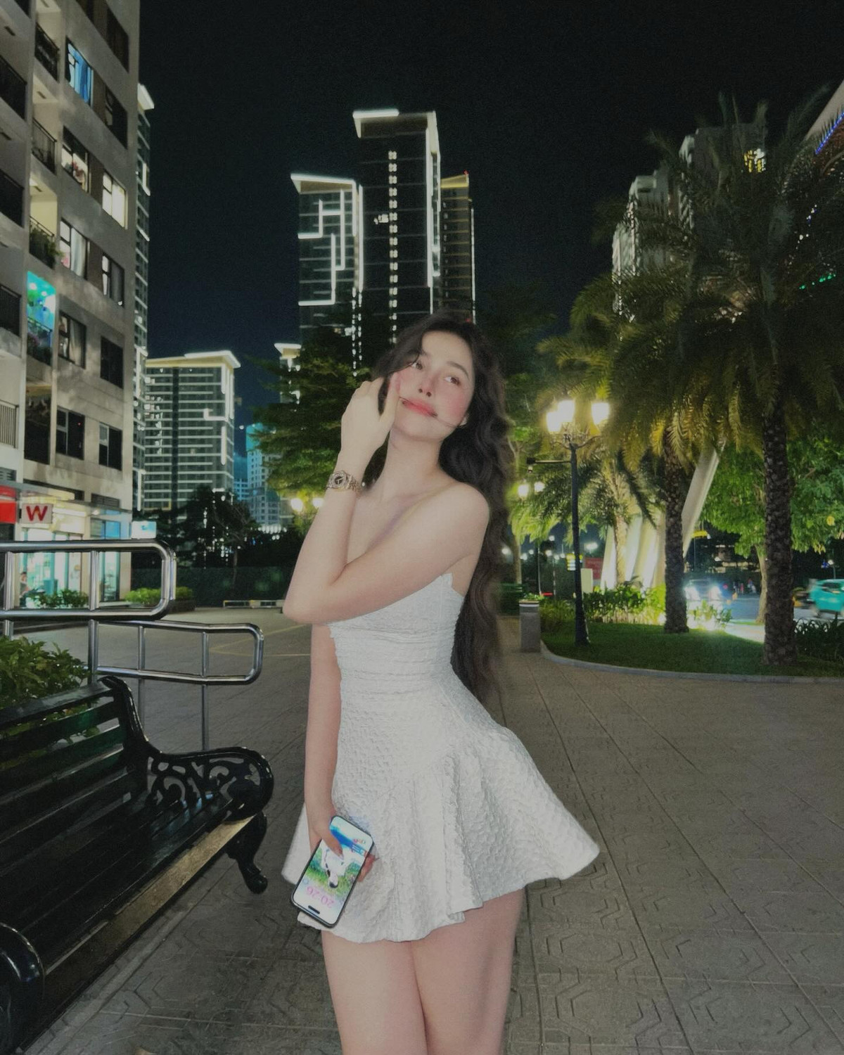 Diện bộ váy trắng ôm sát dáng, Hồng Vy không chỉ tôn lên đường cong quyến rũ mà còn toát lên thần thái rạng rỡ đầy sức sống, khiến khung cảnh thành phố về đêm như trở nên thơ mộng hơn hẳn.