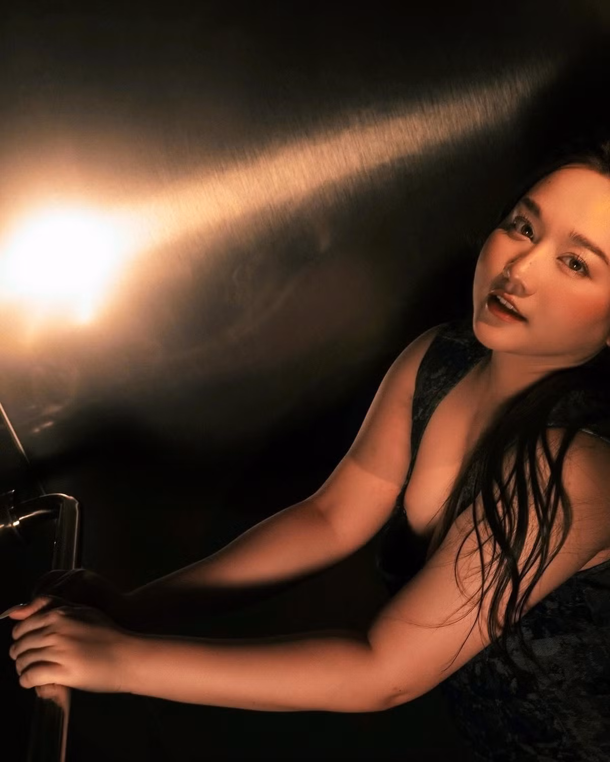 Khung cảnh chụp hình với ánh sáng lạnh, kim loại và hiệu ứng đèn flash tạo nên cảm giác như một thước phim noir – nơi Trúc Anh hiện lên không còn là một “nàng thơ” bị bó buộc, mà là một người phụ nữ dám đối mặt với sự thay đổi và làm chủ hình ảnh của mình.