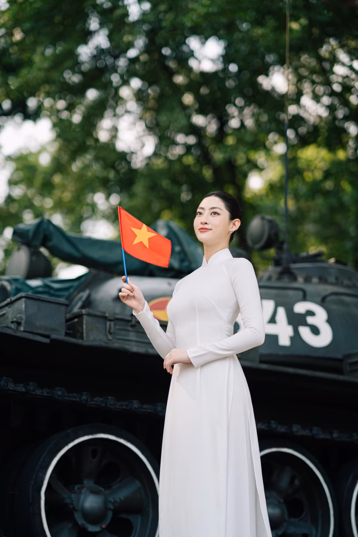 Miss World Vietnam 2019 Lương Thùy Linh lựa chọn tà áo dài trắng thướt tha, cờ tổ quốc và nón lá, nàng hậu chụp cùng chiếc xe tăng huyền thoại.