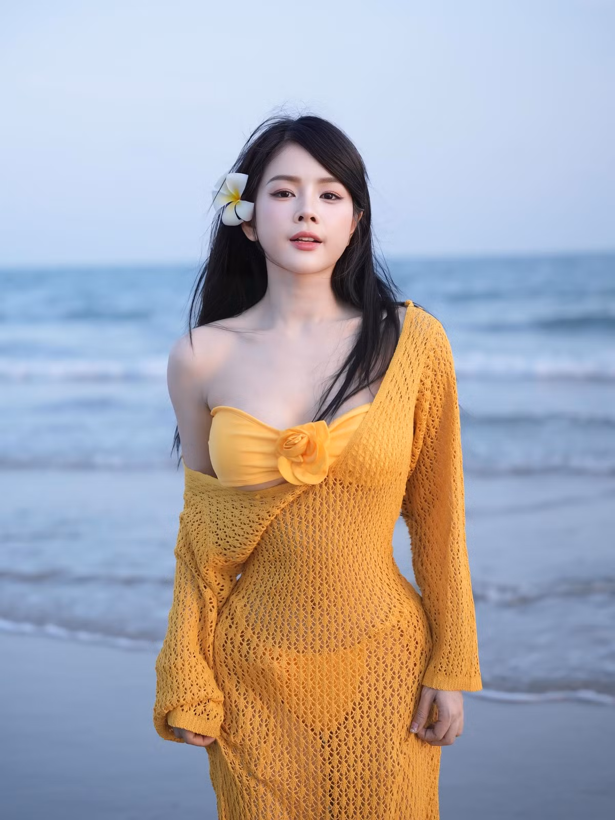 Từng chi tiết trên trang phục đều có chủ ý tôn vinh vóc dáng: tay áo dài buông nhẹ giúp đôi tay trông thon gọn hơn, trong khi phần eo được nhấn khéo léo, tạo cảm giác đường cong uốn lượn mềm mại. Màu vàng tươi không chỉ phù hợp với khung cảnh biển xanh cát trắng, mà còn làm nổi bật làn da sáng và mái tóc đen óng của cô.