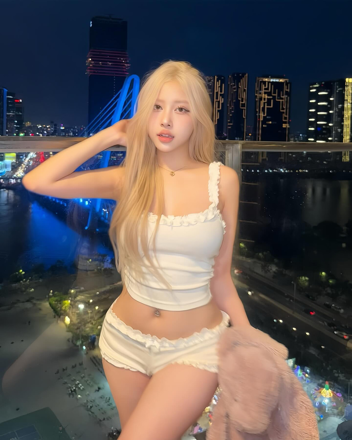 Nổi bật giữa khung cảnh đêm rực rỡ ánh sáng, mái tóc vàng bạch kim của cô nàng như phát sáng. Làn da trắng bật tông, gương mặt makeup glowy tông hồng baby càng khiến tổng thể vừa mang nét ngây thơ lại vô cùng quyến rũ.