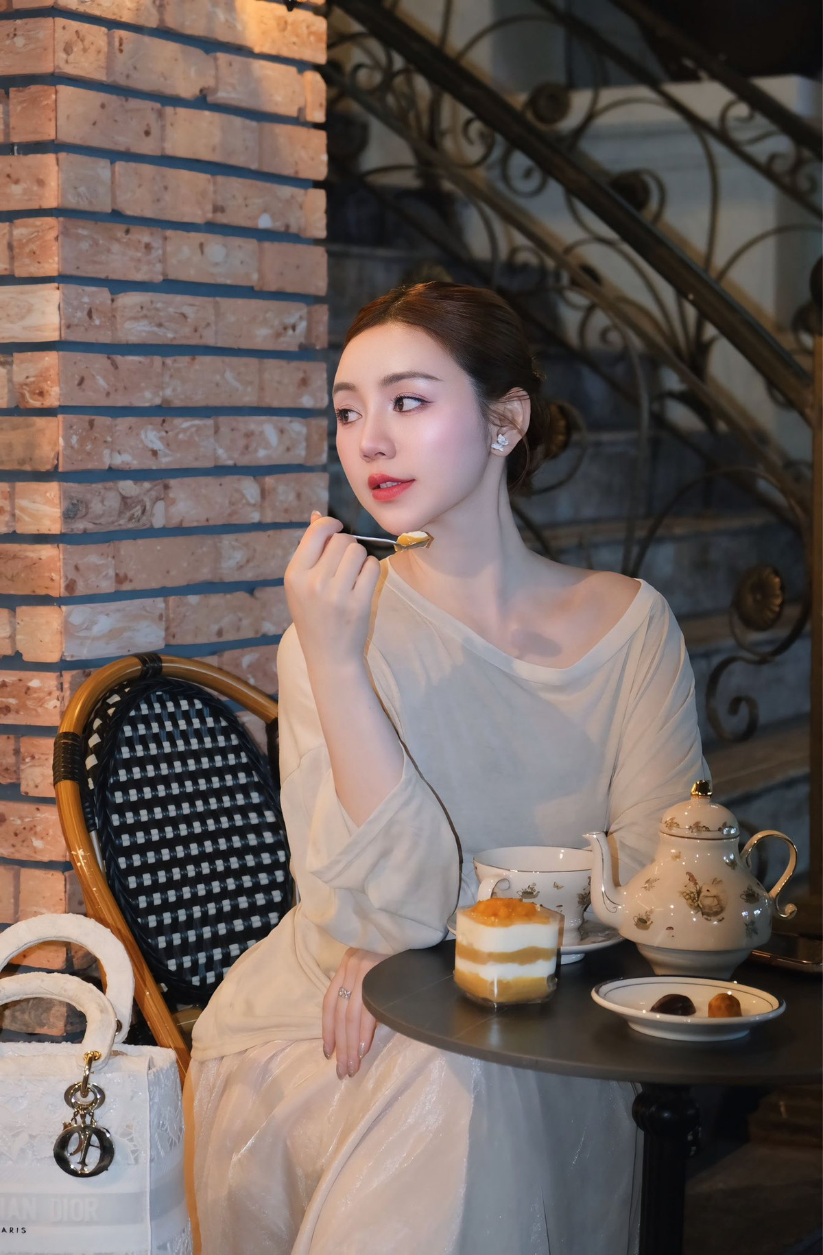 Trong bối cảnh quán cà phê cổ điển và chiếc cầu thang sắt nghệ thuật, Quỳnh Kool nổi bật như một nàng thơ đích thực.