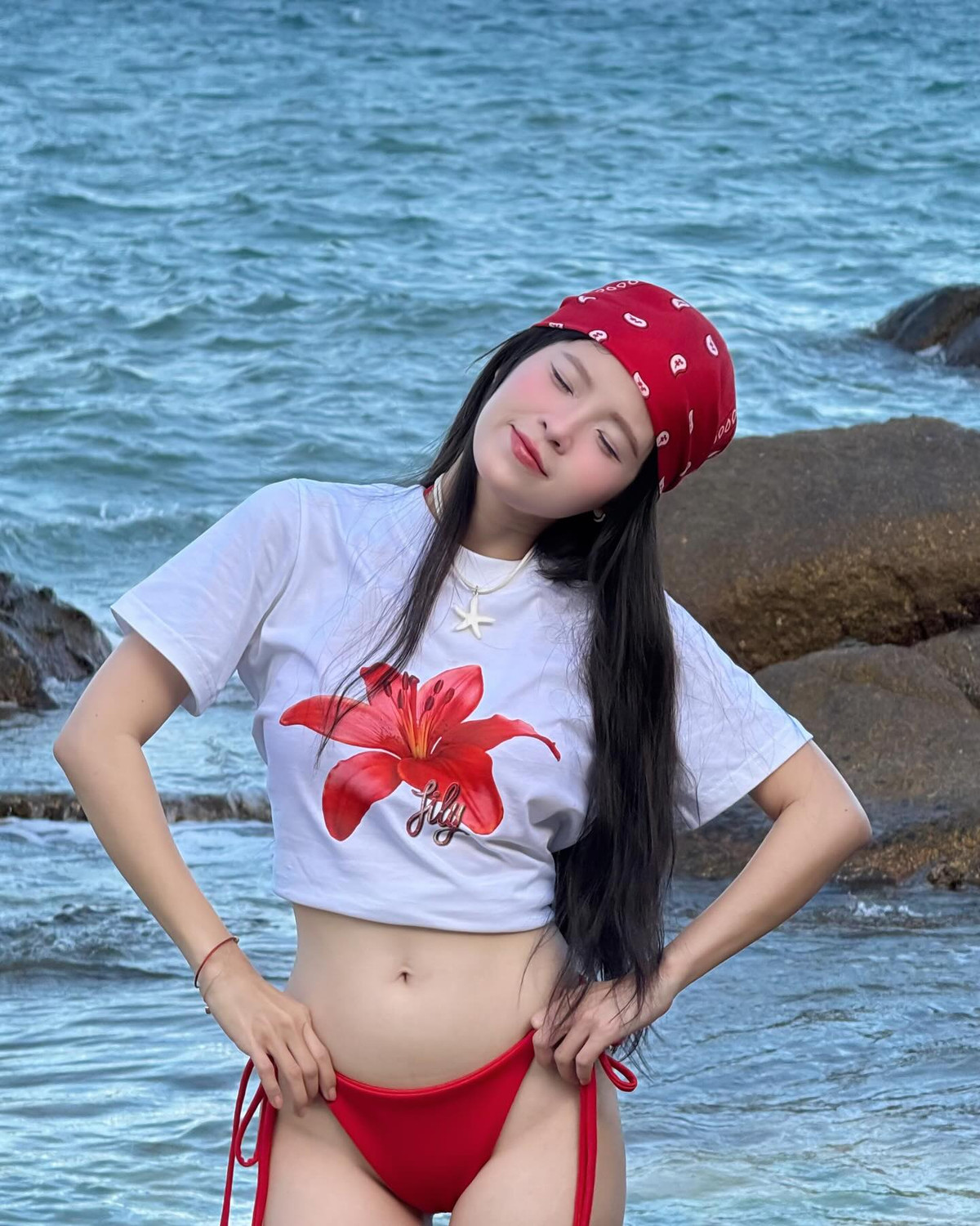 Trong bộ outfit mix giữa áo thun croptop in hình hoa lily nổi bật và bikini đỏ rực, Thúy Kiều khiến dân tình không thể rời mắt.