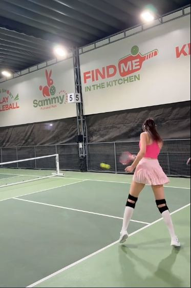 Chiếc mũ lưỡi trai trắng, túi thể thao khoác hờ và nụ cười tươi rói càng khiến cô như một “Barbie thể thao” bước ra từ poster phim điện ảnh.