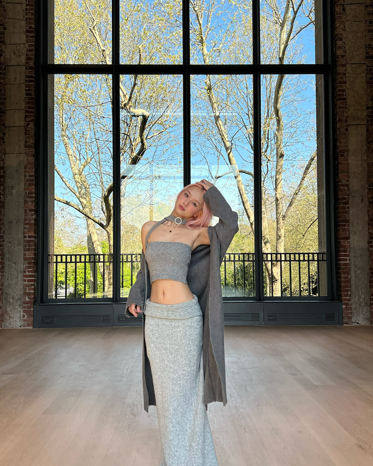 Trong một loạt ảnh, Vyvan diện một set knitwear xám tro gồm crop-top quây và chân váy maxi đồng bộ, khoác ngoài một chiếc cardigan dài cùng tông.