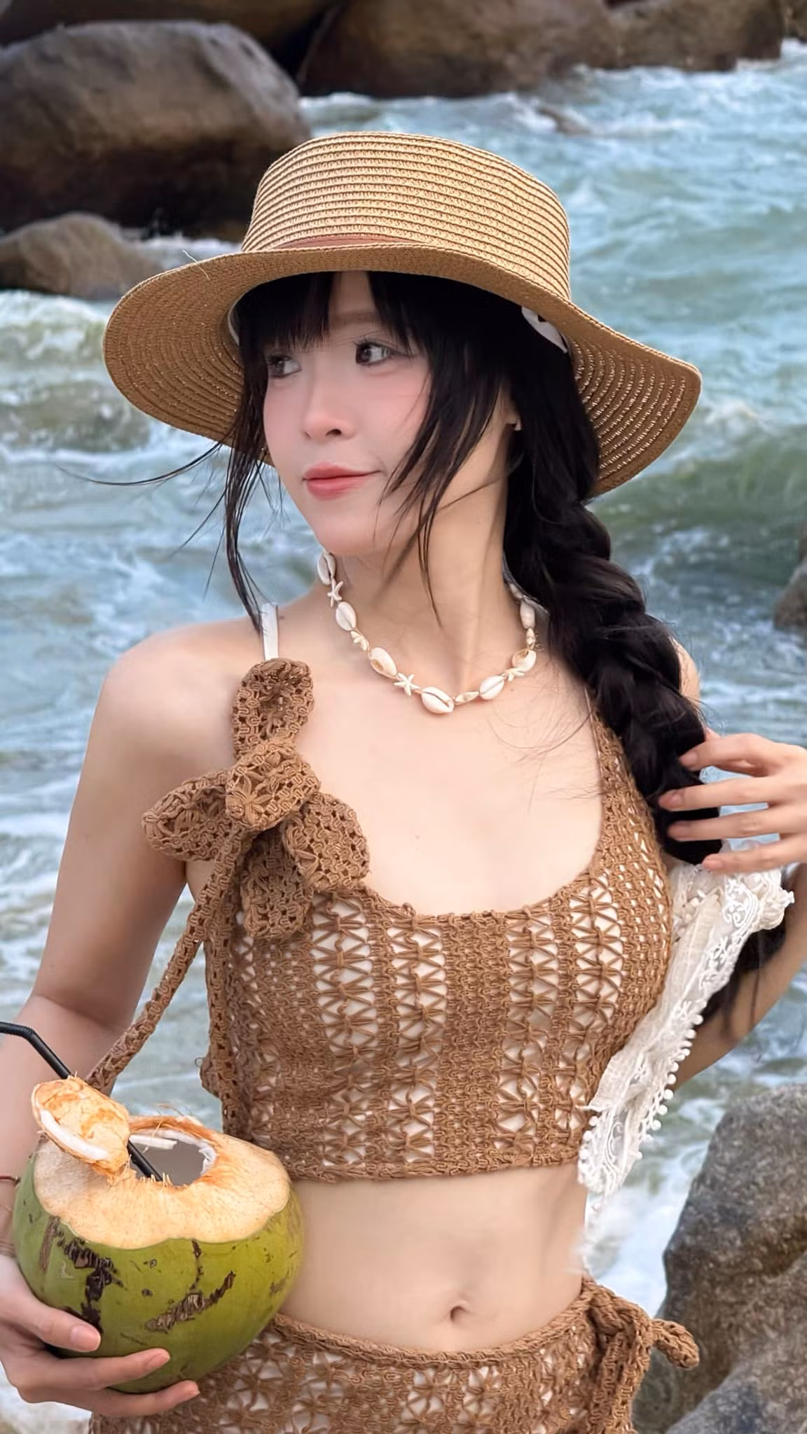 Chất liệu len thoáng mát, họa tiết đan tay tỉ mỉ và gam màu nâu đất mang hơi thở của đất trời miền nhiệt đới, giúp người mặc hòa quyện vào khung cảnh thiên nhiên mà vẫn nổi bật theo cách riêng.