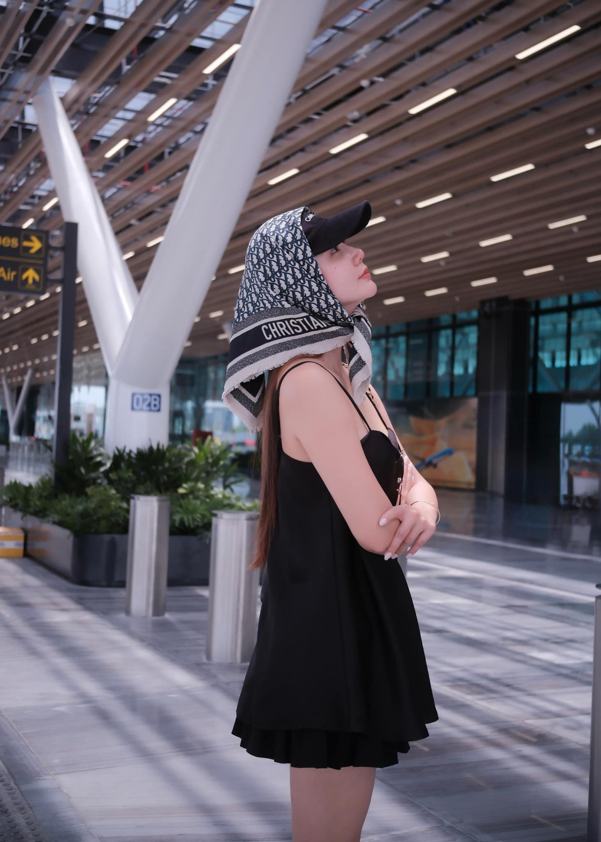 Mái tóc dài suôn mượt được buông xõa tự nhiên, ẩn hiện dưới lớp khăn và mũ, mang đến vẻ đẹp vừa thanh thoát vừa quyến rũ, như một quý cô Pháp hiện đại vừa bước xuống từ chiếc xe hơi cổ điển.